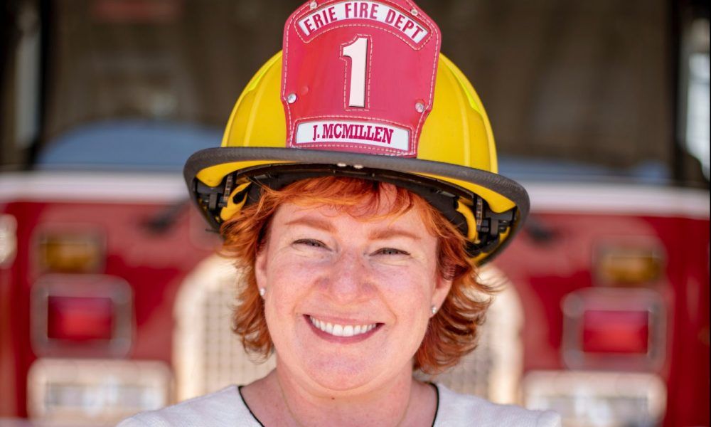 Jenn McMillen Founder of Incendio and Chief Accelerant wearing firefighter hat in front of fire truck